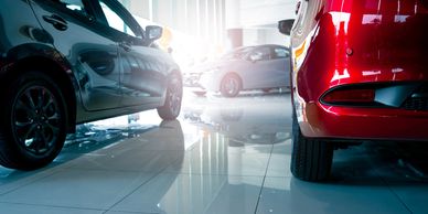 Shiny new cars displayed in a bright showroom with polished tile floors.