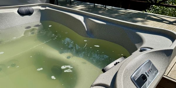 Dirty hot tub with cloudy green water prior to professional TheraSpa maintenance