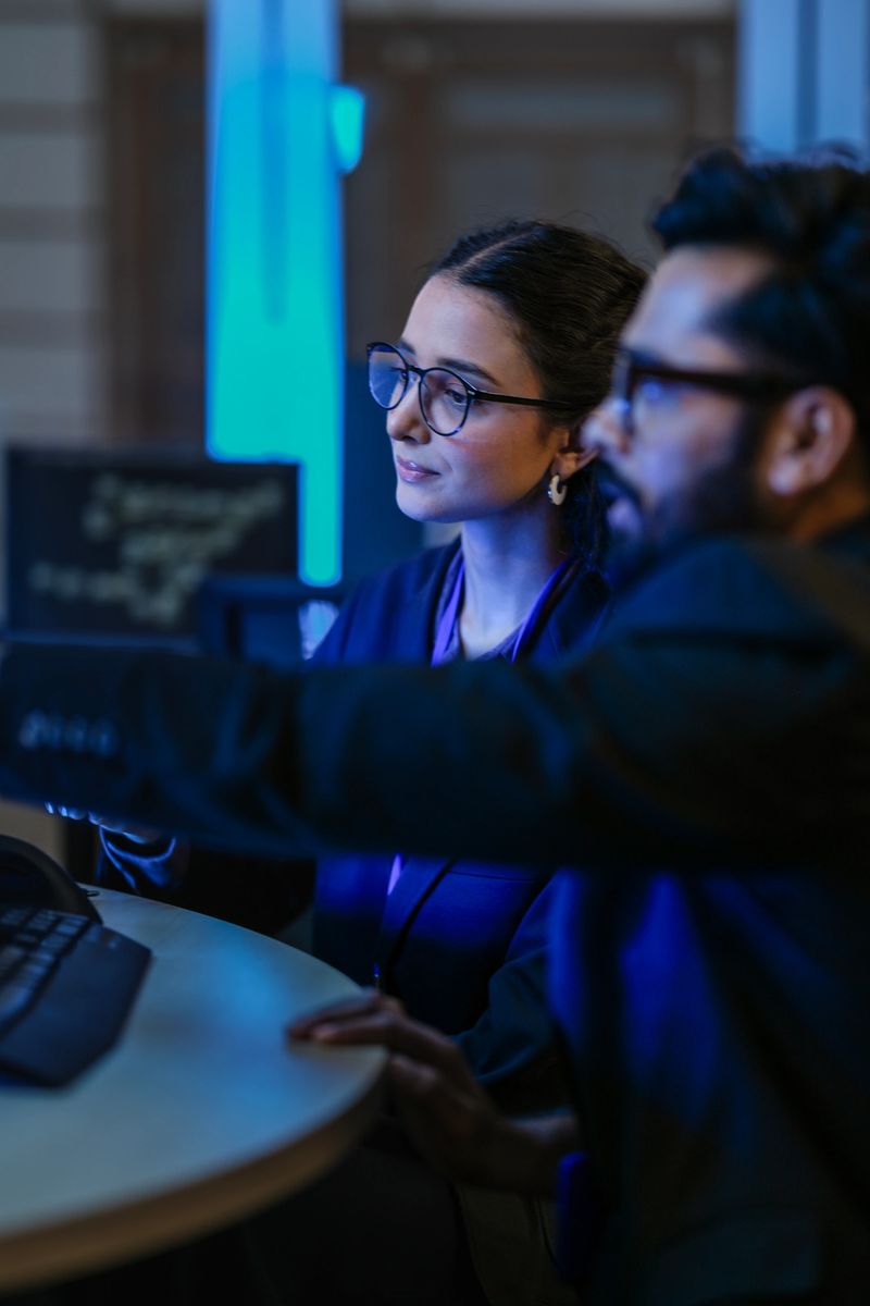 A diverse team of AI developers shares a successful moment in the office. A female programmer smiles as they review the positive results of a complex machine learning algorithm.