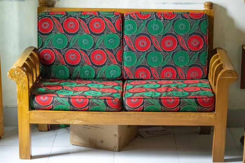 Close-up of a modern two-seater wooden sofa set in a cozy living room, highlighting rustic craftsmanship, comfort, and interior design.