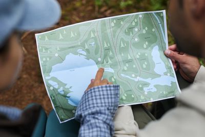 Two people examining a map outdoors, one pointing at a location.