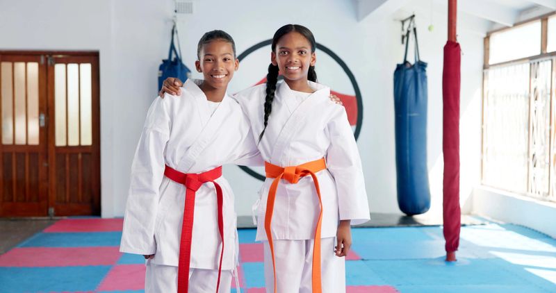 Hug, karate and portrait of students in dojo for martial arts, self defense or sports training. Development, fitness and smile of child friends embracing in class together for exercise or workout