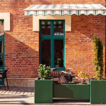 Green plants in modern planter boxes outside a brick building.
