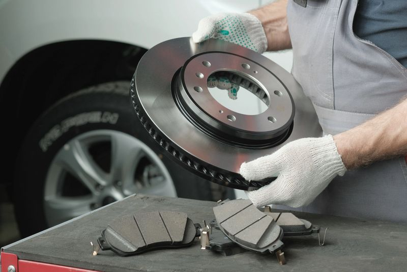 On the desktop, an auto mechanic inspects and controls spare parts-a new brake disc and a set of brake pads.