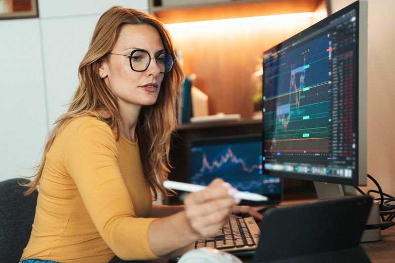 A young woman is sitting in her home and attentively observing the stock market using cryptocurrency graphics
