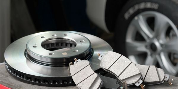 Car brake rotor and brake pads placed on a table.