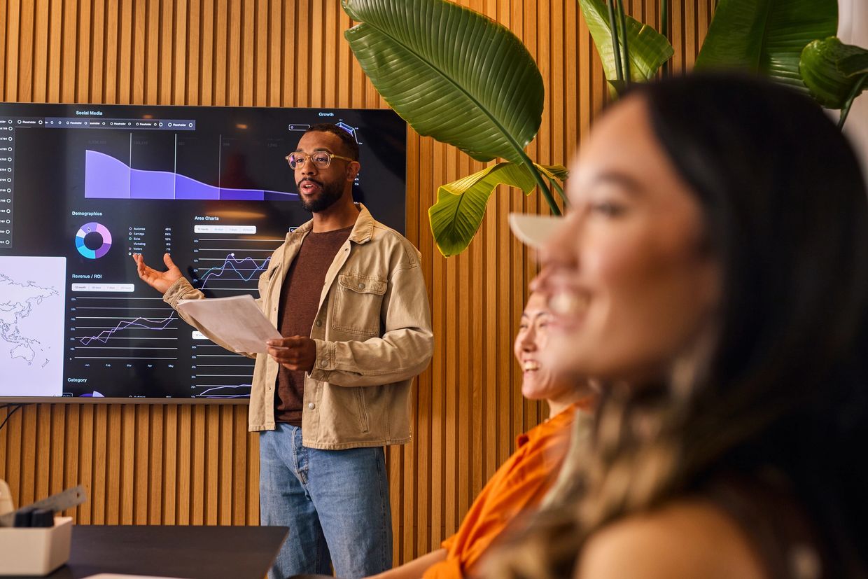 A man presenting data charts to a group in a modern office setting.