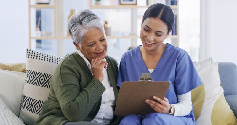 Clipboard, nurse and advice with old woman on sofa for evaluation, treatment progress and medical plan. Healthcare, medicine schedule and checkup list with people in nursing home as caregiver