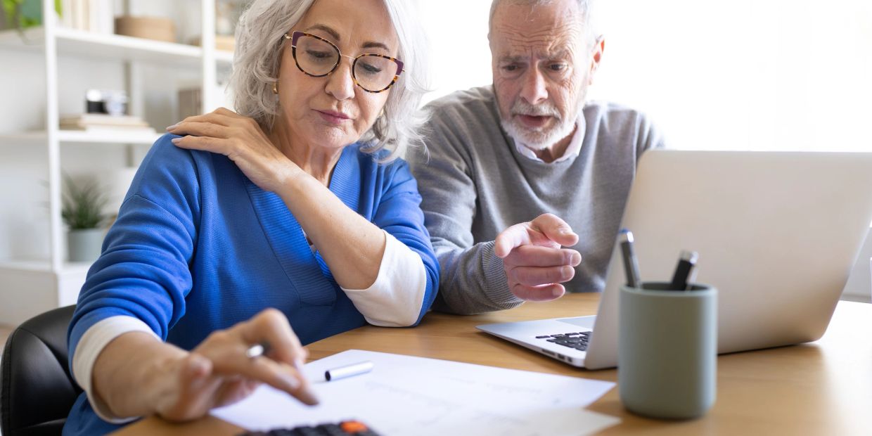 An elderly couple calculating finances together.