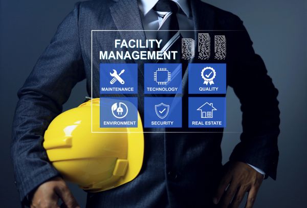 Businessman holding yellow helmet with facility management icons.