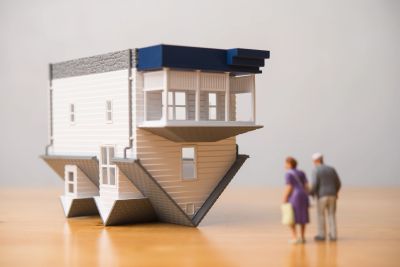 Older homeowners with an upside-down house model, representing reverse mortgages in Ontario real est