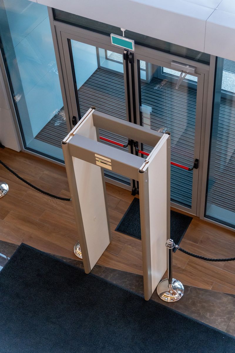 Automatic doors at a modern building entrance with a security metal detector scanner for controlled access and public safety.