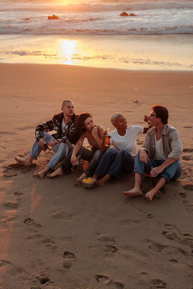 Four friends relaxing on the beach at sunset, enjoying drinks, snacks, and each others company
