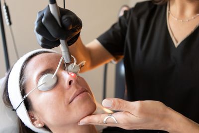 Woman receiving laser treatment on her face with protective eyewear.