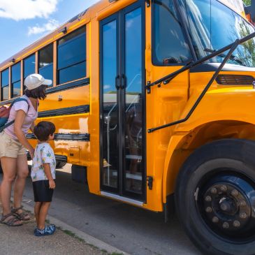 Parent and child boarding a school bus — Transportation Services service card describing routing, op