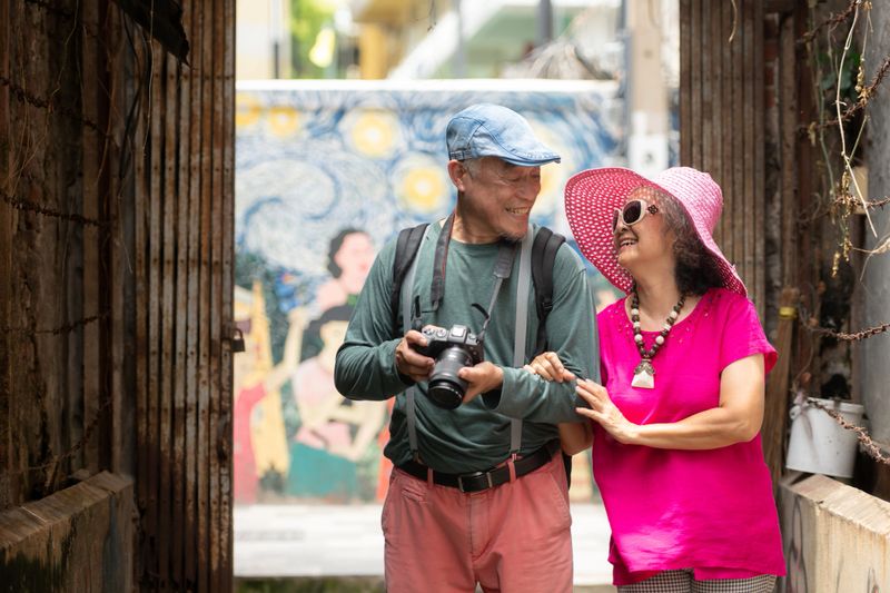 A happy senior couple strolling along a city's old neighborhood, enjoying travel, street exploration, and cultural adventure with smiles and relaxed moments