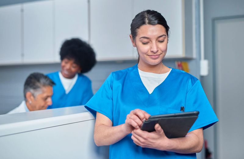 Healthcare professionals collaborate at the front desk area, utilizing technology such as tablets to enhance efficiency, portraying teamwork, modernization, and attentive patient care.