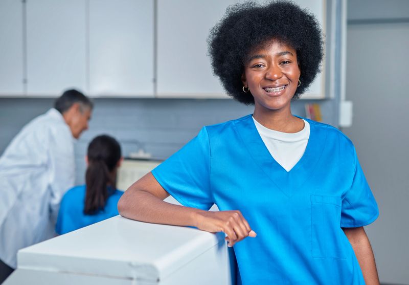 Professional healthcare worker in a clinic setting, showcasing positive demeanor and readiness for excellence while assisting with patient care. Highlighting teamwork and modern medical facilities.