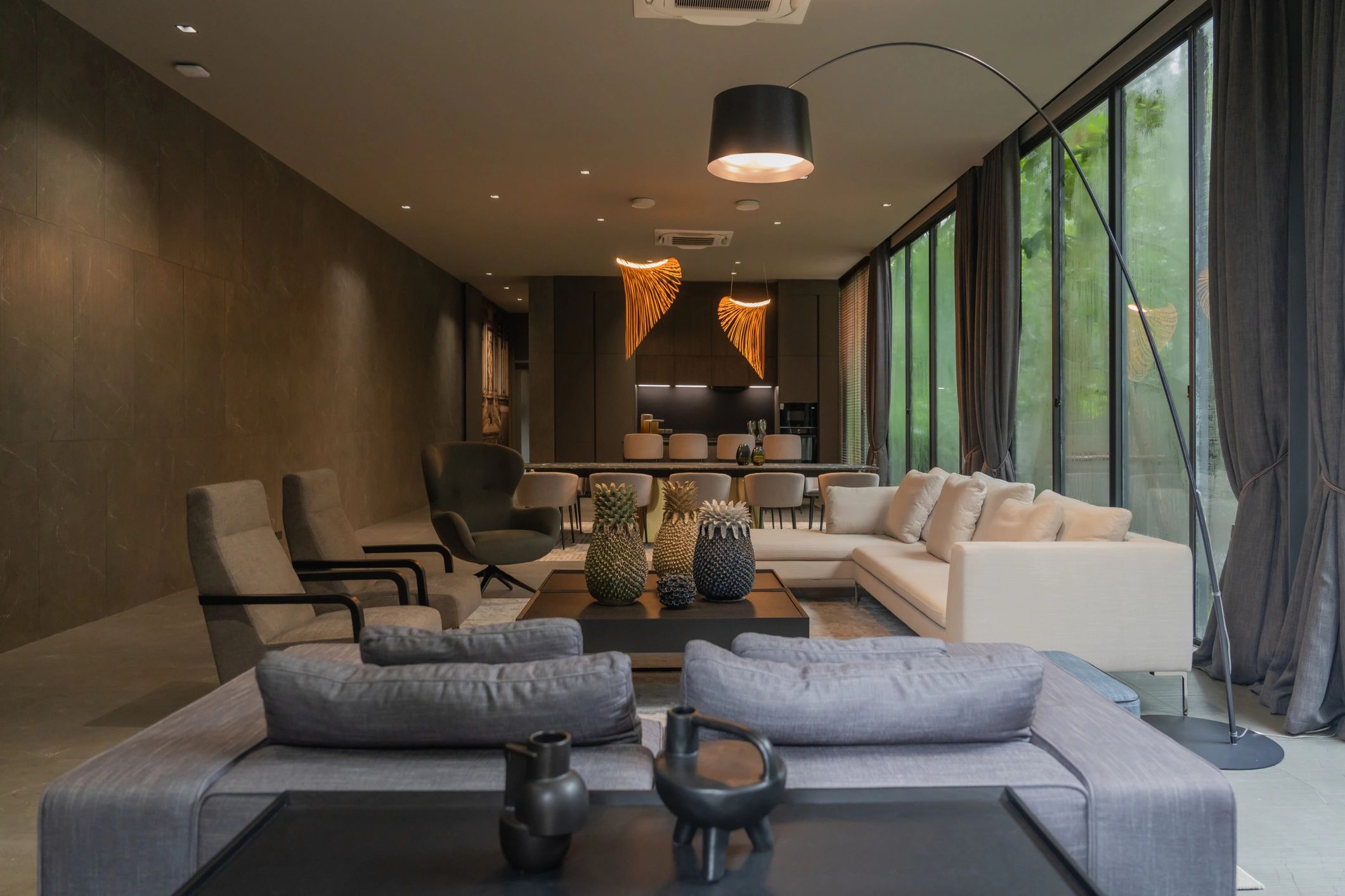 Modern living room with large windows, cozy sofas, and artistic lighting.