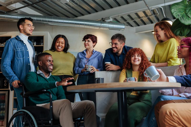 Coworkers enjoying a coffee break together, discussing and smiling in a modern office environment