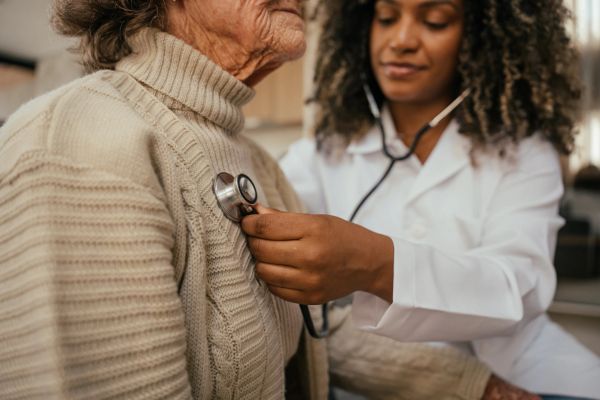 Doctor using stethoscope on elderly patient.