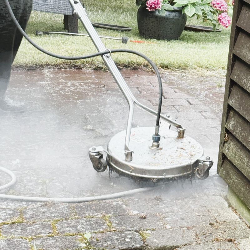 A person operating a high-pressure water cleaning machine on outdoor cement paving stones. The strong water jet removes dirt, algae, and weather stains, bringing the stone surface back to life. Concept of patio cleaning, outdoor maintenance, and surface restoration.