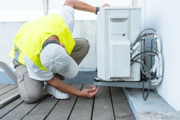 Technician inspecting an outdoor air conditioning unit.