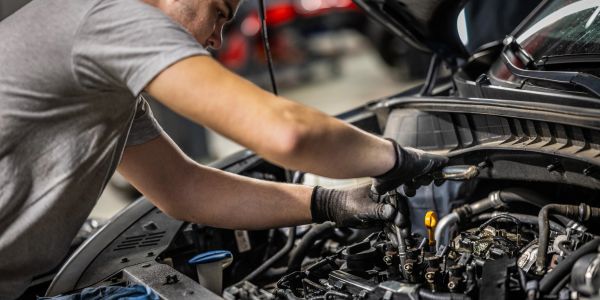 Mechanic working on car engine with tools.