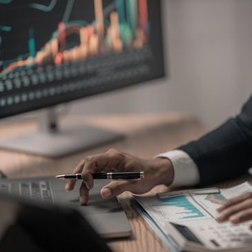 Person analyzing financial charts with a laptop and pen.