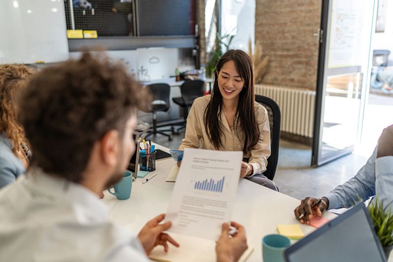 Group of diverse business professionals reviewing financial data during a productive meeting in a bright, modern office space, fostering collaboration and strategic decision-making