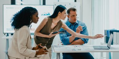 Three professionals collaborating around a laptop in an office.
