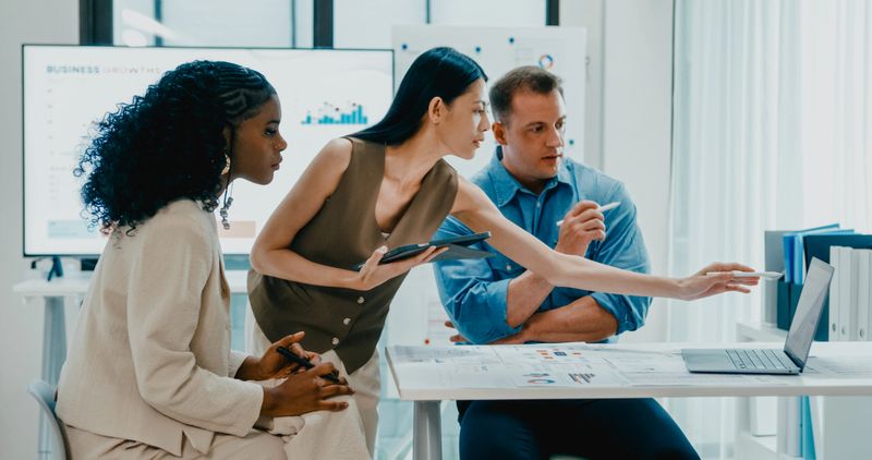 Diverse finance team business meeting discussing investment strategy and financial report presentation on laptop at office. Marketing strategy analysis, financial consultant concept.