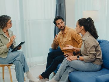 Couple discussing relationship issues with a therapist in a cozy room.