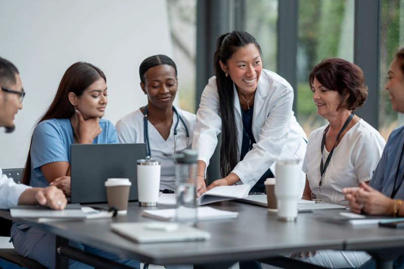 Healthcare professionals of diverse backgrounds discussing and collaborating during a meeting, showcasing teamwork and inclusivity in a modern environment.