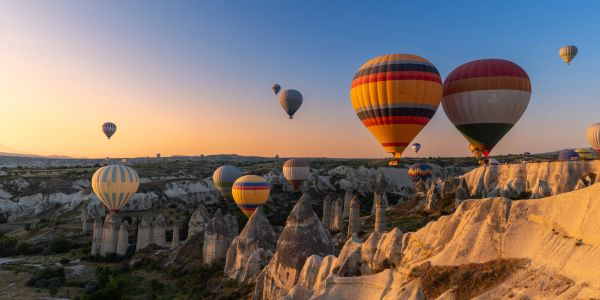 Colorful hot air balloons over rocky landscape at sunrise.