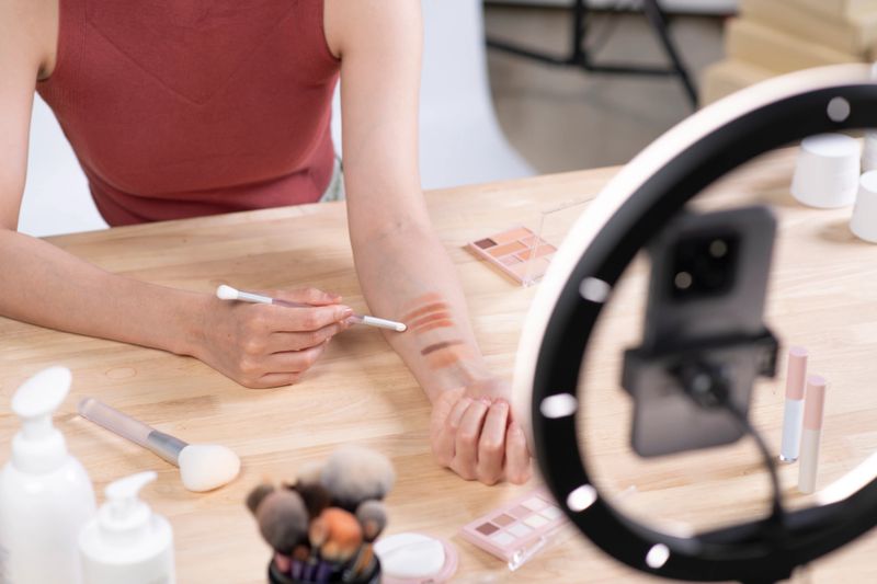 Young beautiful Asian woman and professional beauty make up artist vlogger or blogger recording makeup tutorial to share on website or social media. Business online influencer on social media concept.