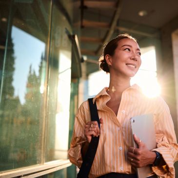 Smiling woman with a laptop and backpack.