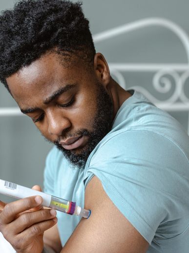 Man administering an injection to his upper arm using an auto-injector.