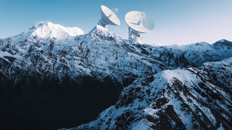 Two massive satellite dishes overlook the icy mountains, designed for communication with distant satellites and deep space probes. The scene represents the fusion of technology and wilderness.