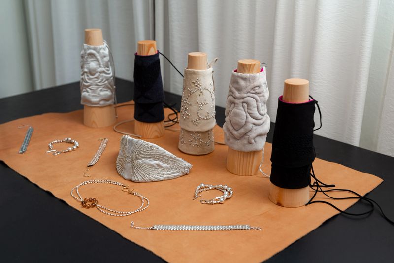 A stylish display featuring intricately designed textile patterns on wooden stands, complemented by an array of elegant jewelry pieces on a leather surface. perfect for fashion and design inspiration.