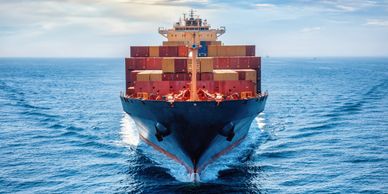 A large cargo ship loaded with containers sailing on calm waters.