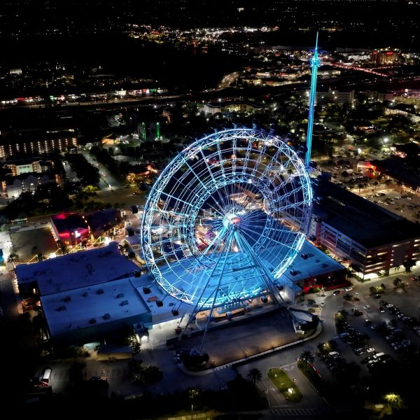 Night view of a large illuminated Ferris wheel in a city.