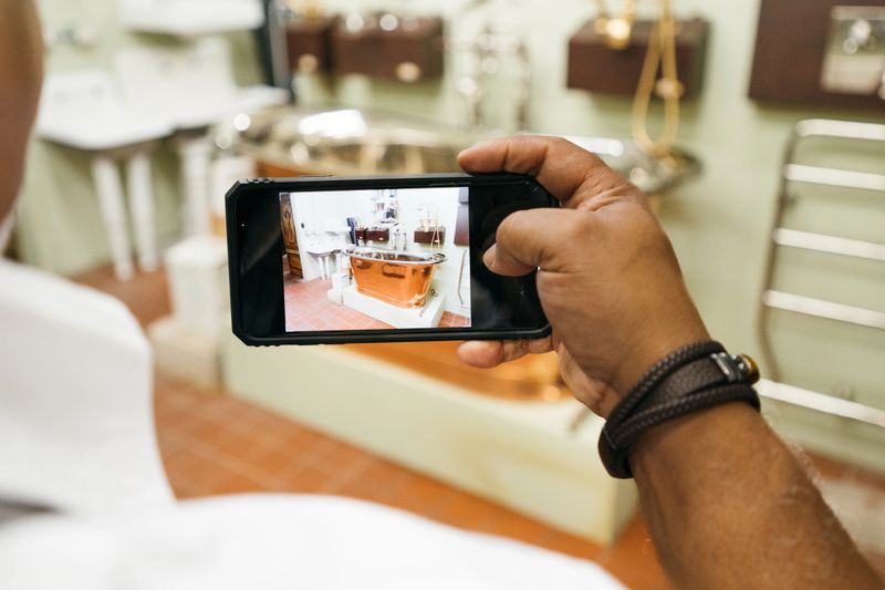 Over the shoulder view of person taking a photo of a retro bathtub