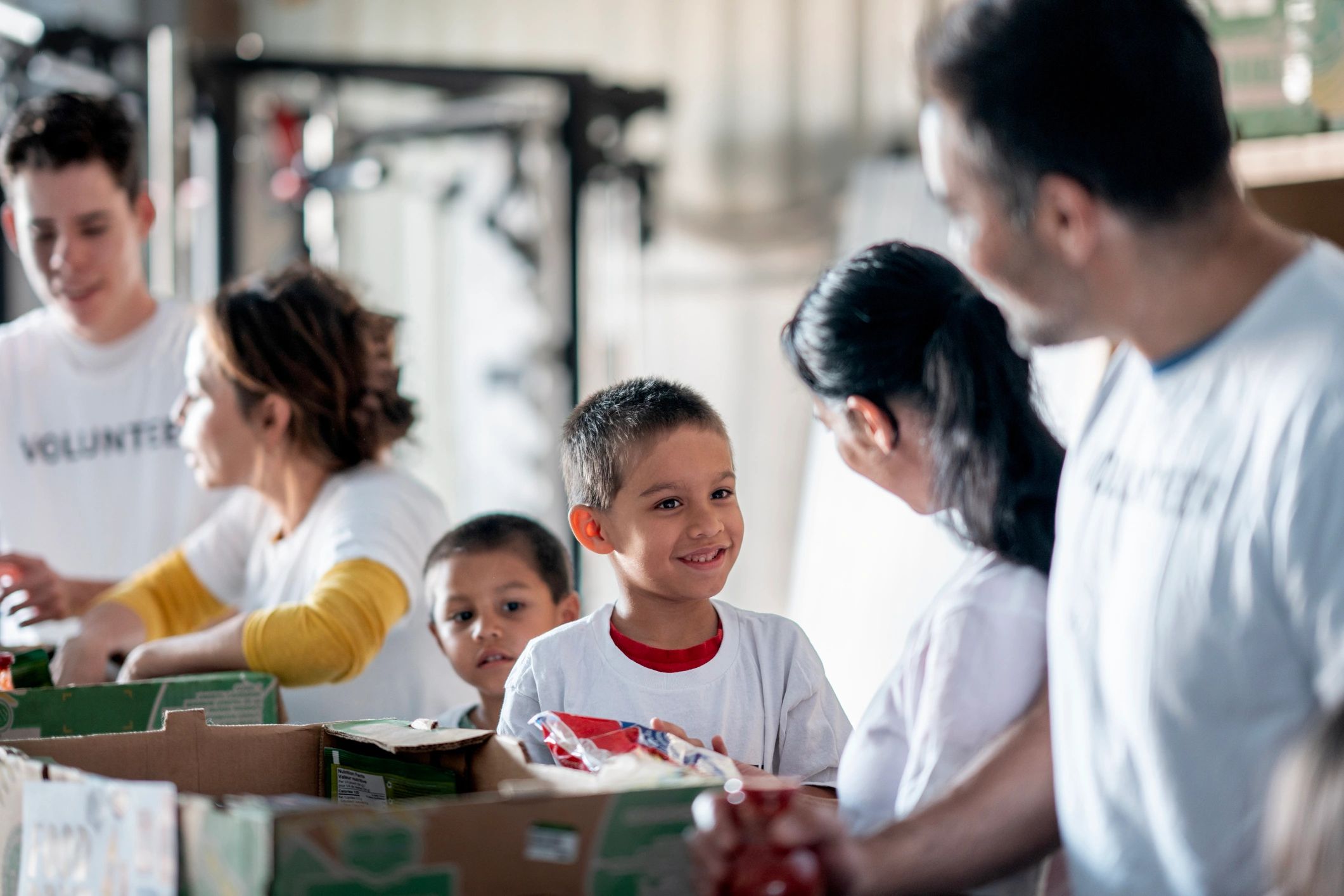Volunteers and children packing food boxes together.