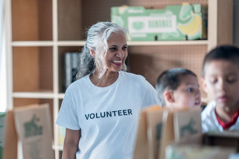 A cheerful volunteer interacts with children while aiding in food donation activities at a community center, showing support and kindness.