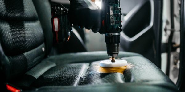 Using a drill to clean a car seat.