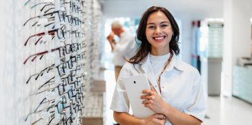 Smiling optometrist holding a tablet in an eyewear store.