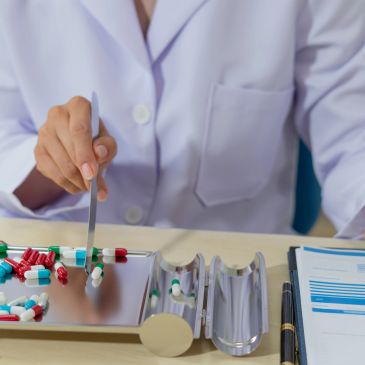 Person in white coat sorting pills on a tray.