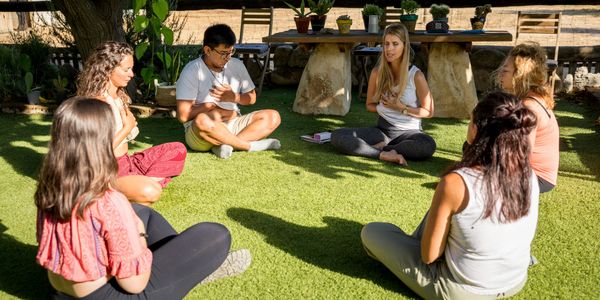 Group of people meditating together outdoors on grass.