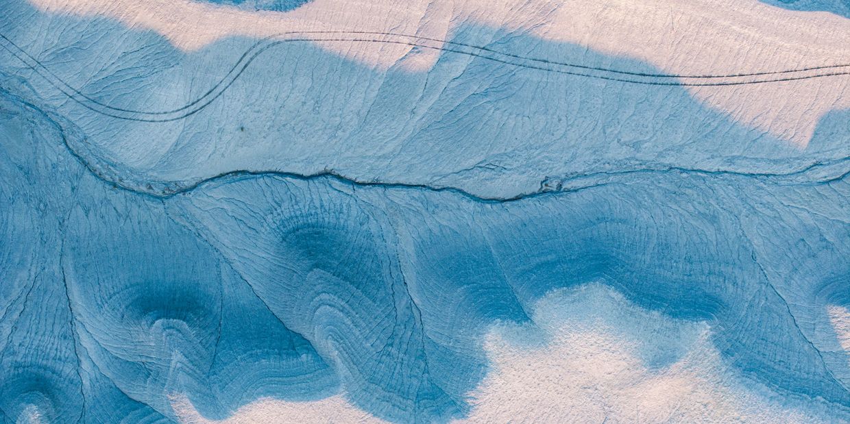 Aerial view of a glacier with blue ice patterns.